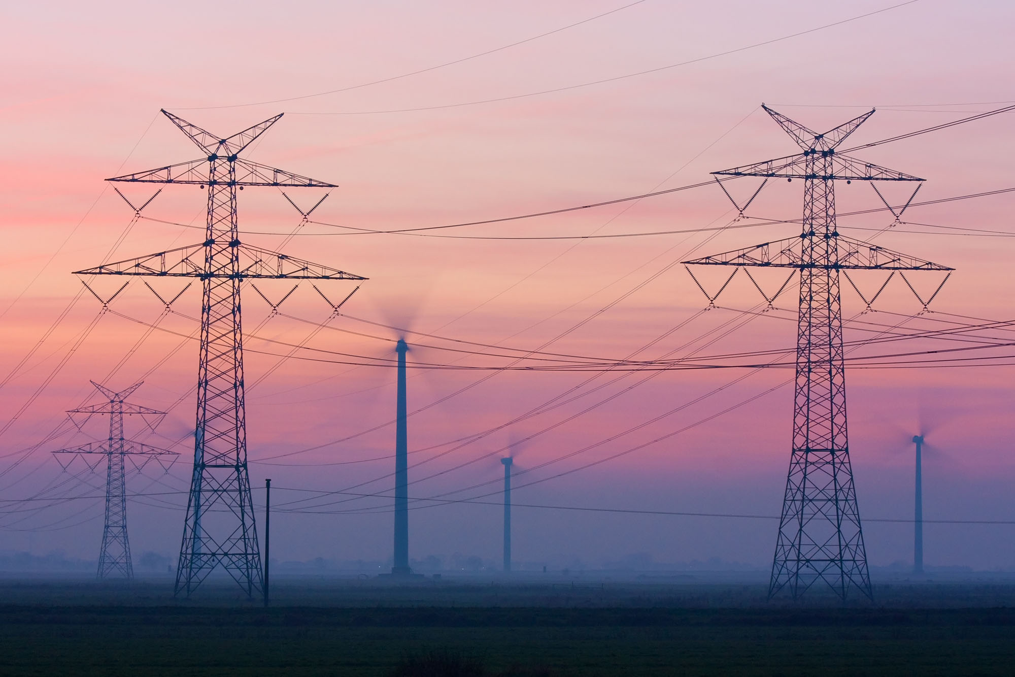 Strommasten und Windräder in Abenddämmerung